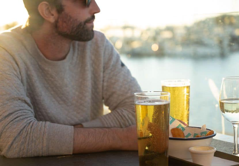 A man drinking beer and looking over the harbour.
