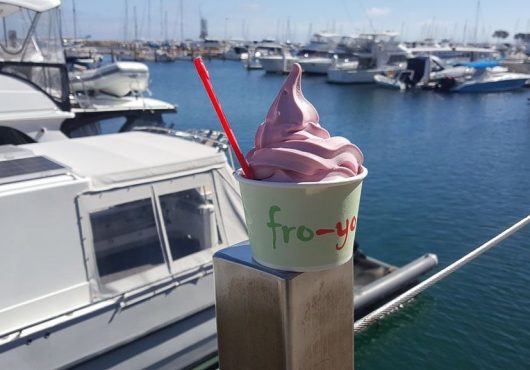 Frozen yogurt sitting on the boardwalk railing.